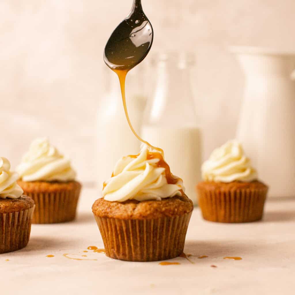 A drizzle shot of the caramel onto the carrot cake cupcakes with applesauce. 
