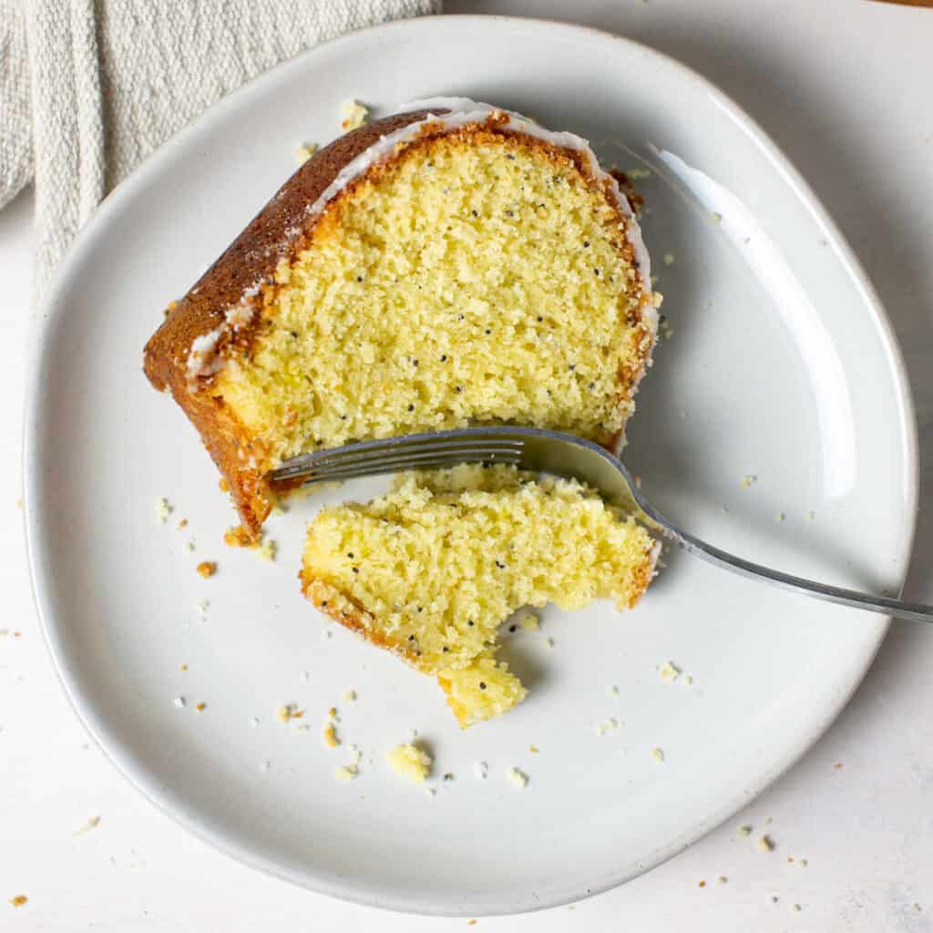 A sliced piece of the lemon poppyseed cake with a bite out of it