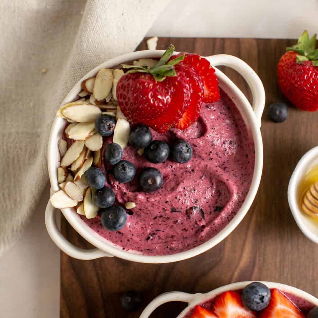 an overhead shot of the berry smoothie bowl with fruit and sliced almonds.