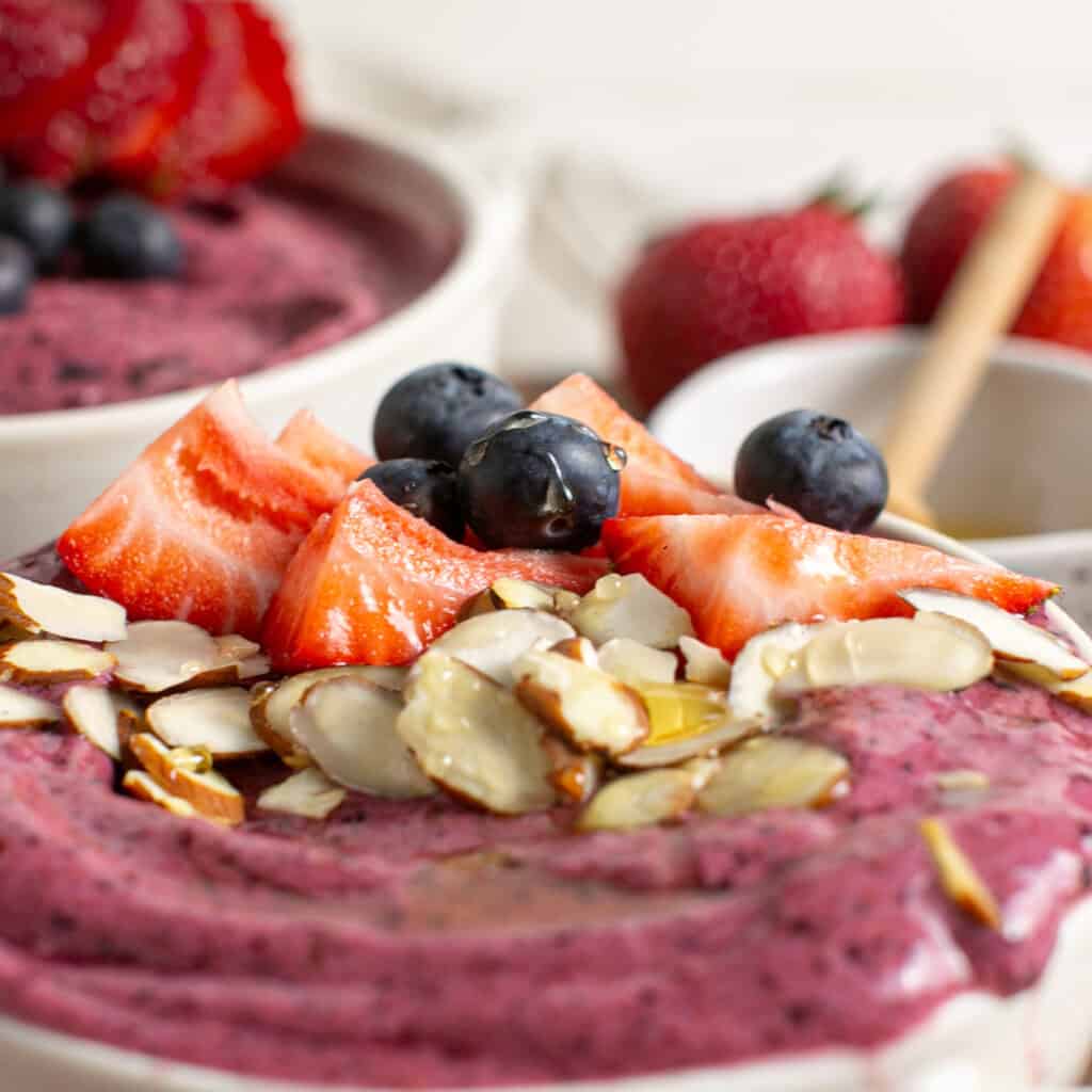 a close up shot of the berries on top of the berry smoothie bowl