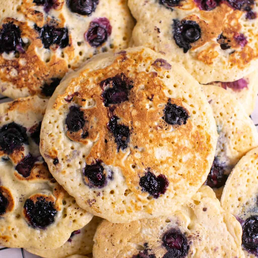 a bunch of blueberry pancakes laying over each other to see the close up of the texture.