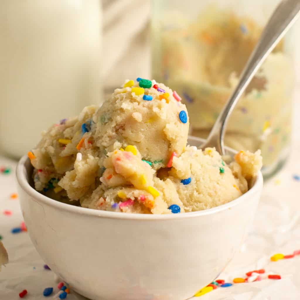 A bowl full of no bake sugar cookie dough topped with extra sprinkles