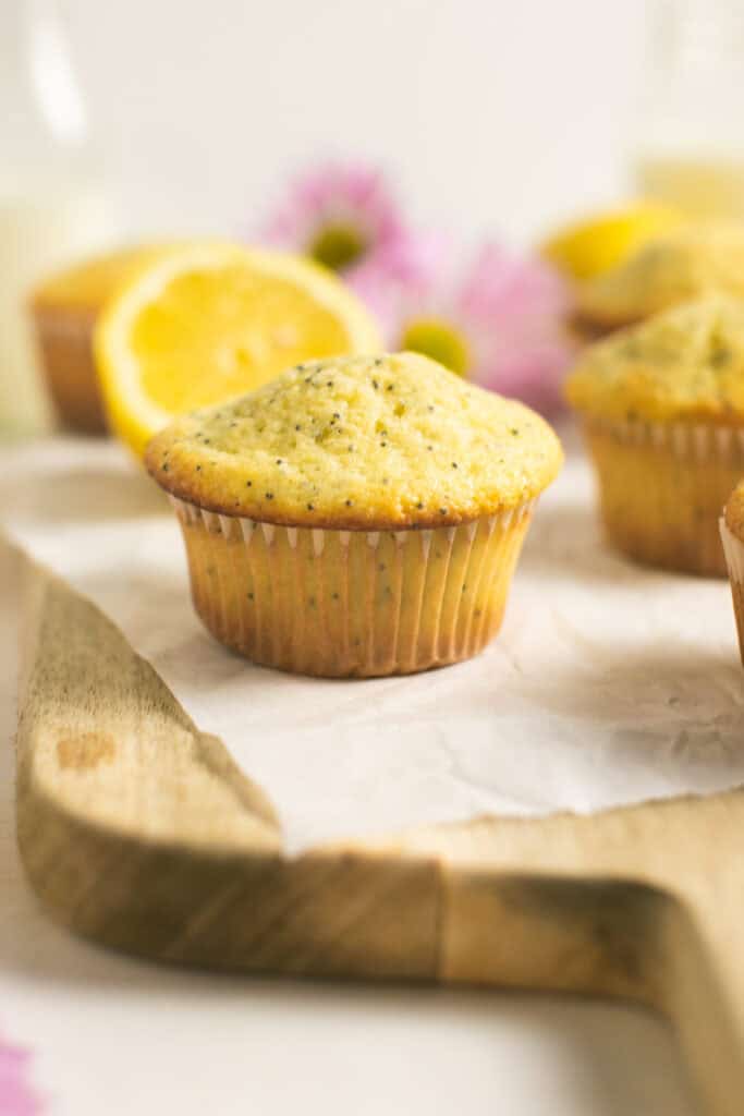 A side shot of the lemon poppyseed muffins sitting on a wooden cutting board