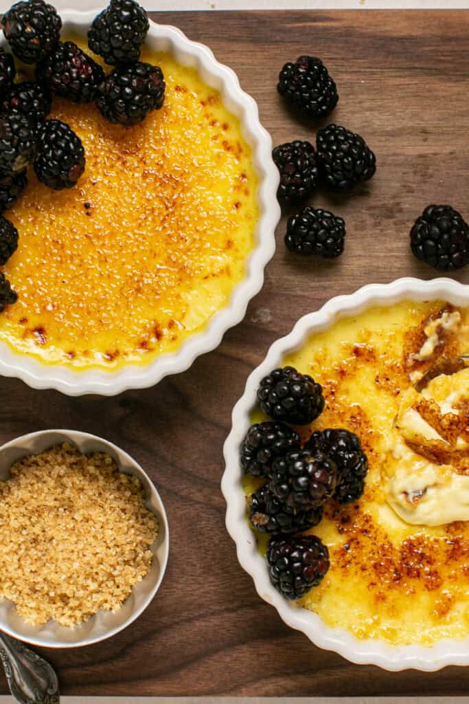 An overhead shot of two vanilla bean creme brulee's with blackberries on the top. 