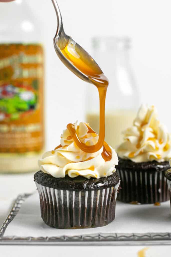 A drizzle of caramel coming down onto the salted caramel cupcakes.