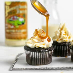 A spoonful of caramel dripping down onto the salted caramel cupcakes