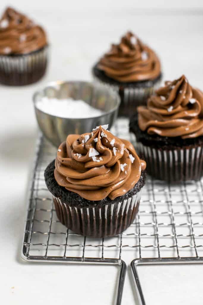 The chocolate Nutella cupcakes sitting on a cooling rack with a jar of salt. 