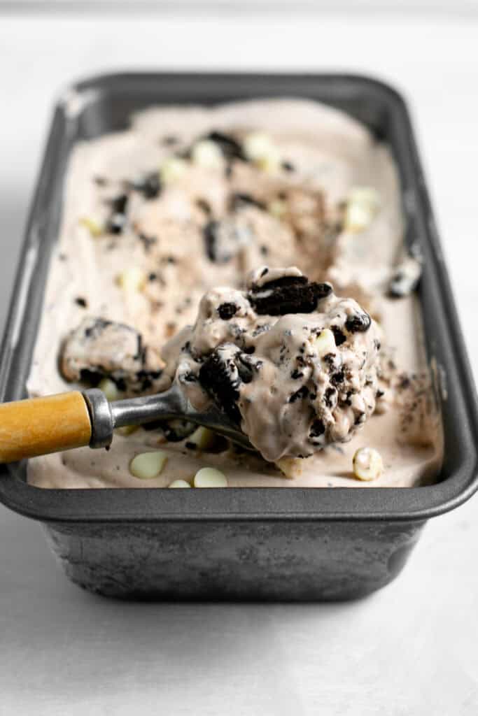 A scoop of the chocolate cookies n cream ice cream in the metal ice cream tin.