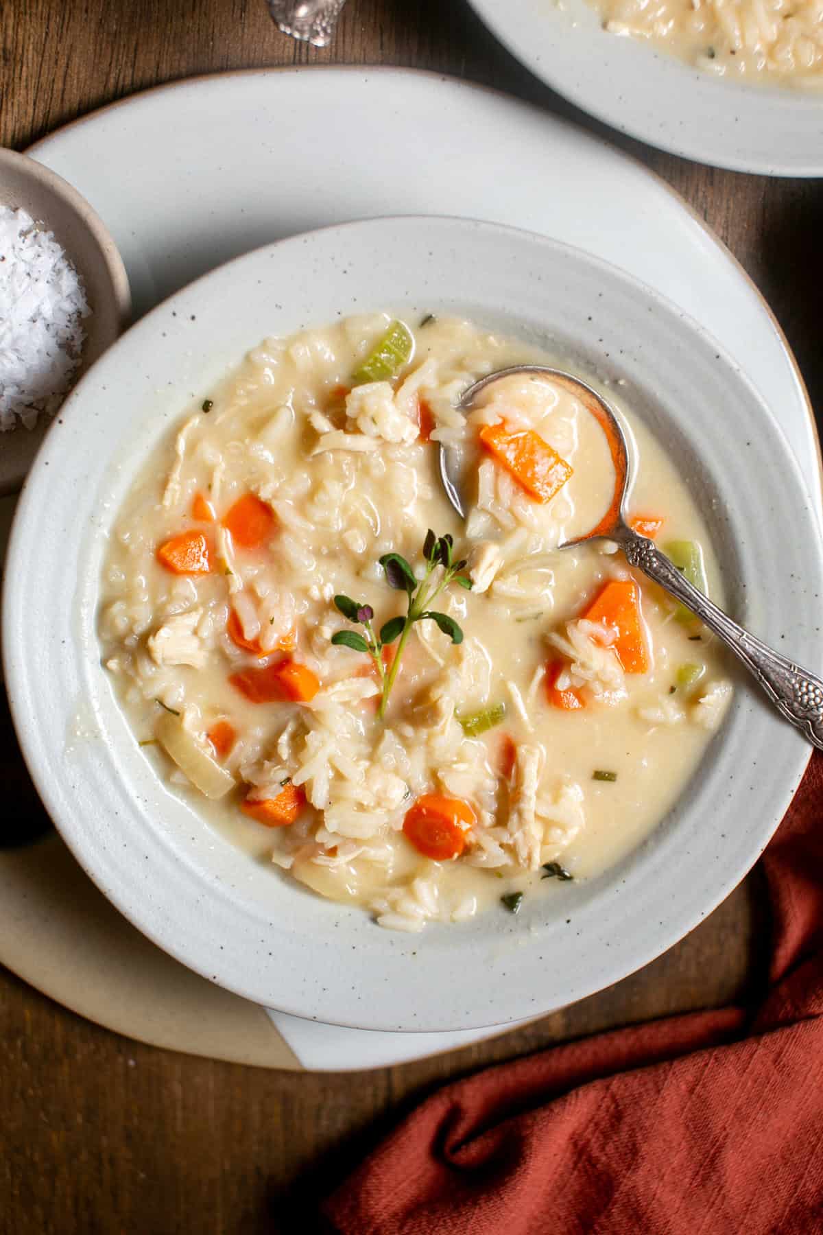 A bowl of chicken and rice soup with a spoon.