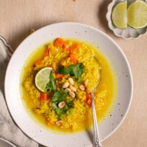 Feel-Good Turmeric Rice Soup by a bowl of lime wedges.