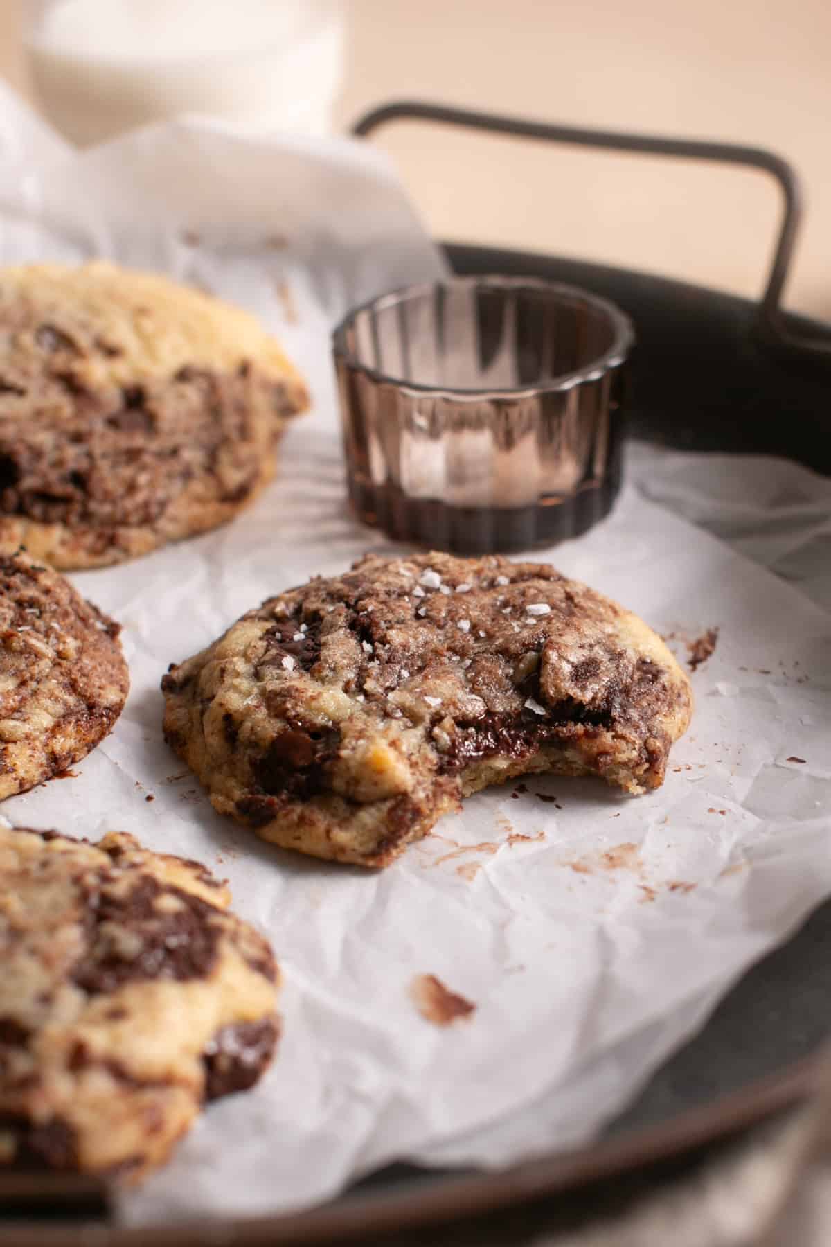 Chocolate Chip Brownie Cookies with a bite missing on parchment paper. 