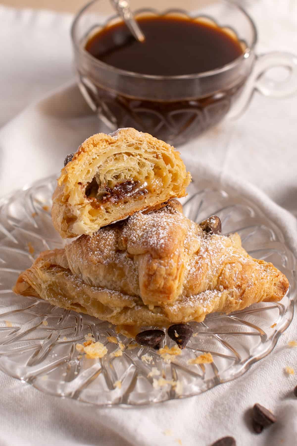 Chocolate Chip Cookie Croissant cut in half by a cup of coffee.