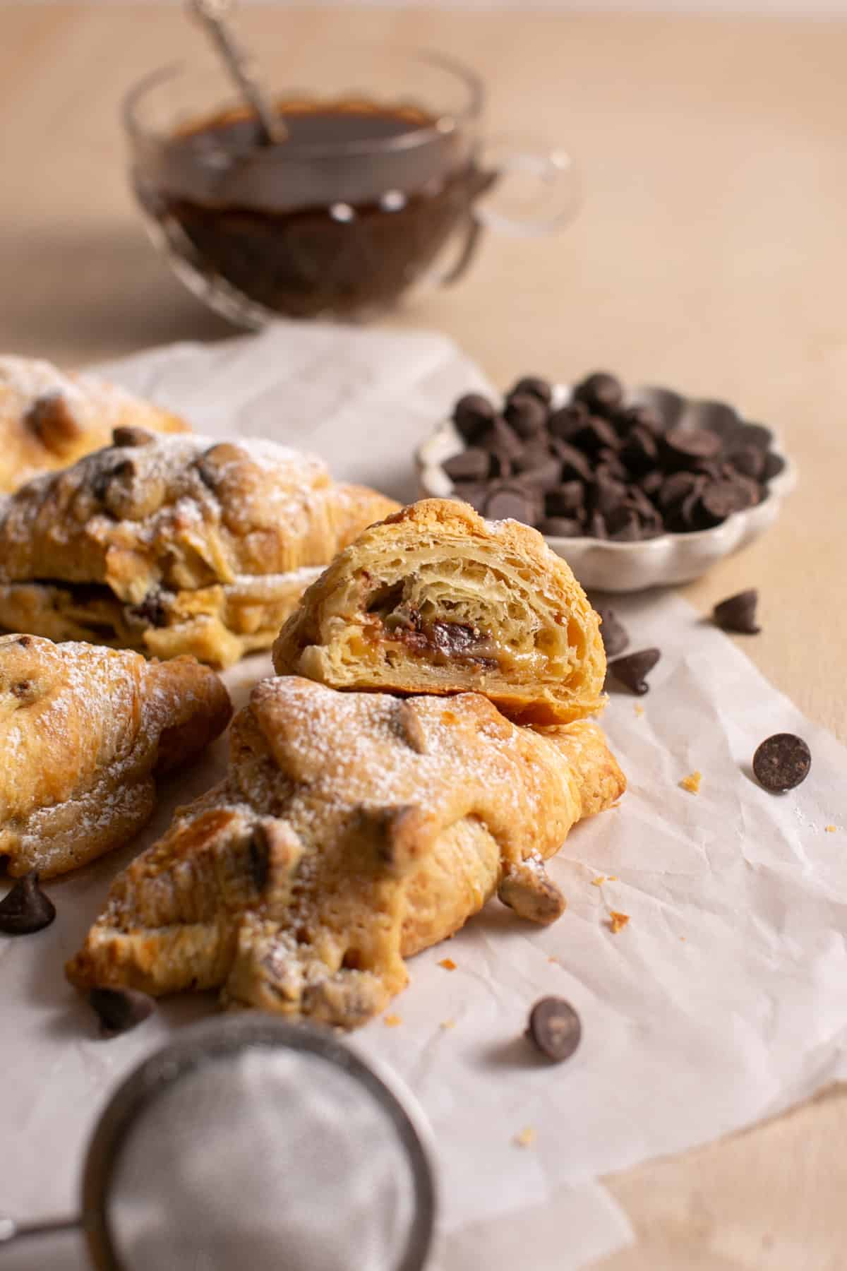 Chocolate Chip Cookie Croissant sitting by a cup of coffee.