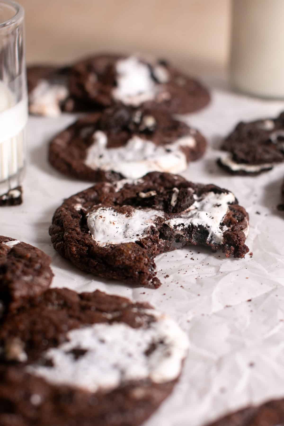 Minty Chocolate Marshmallow Cookies with a bite missing sitting by a glass of milk.