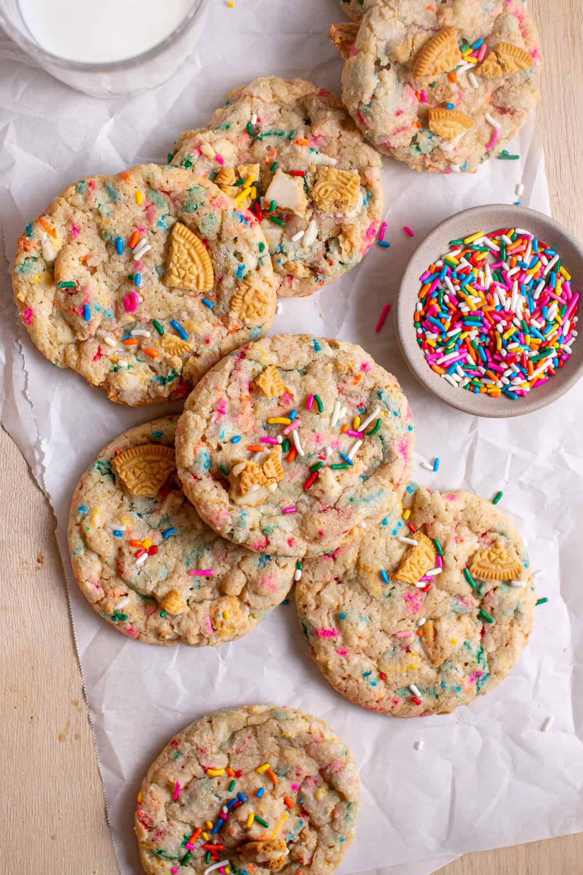 Golden Funfetti Cookies stacked on top of each other by a glass of milk.