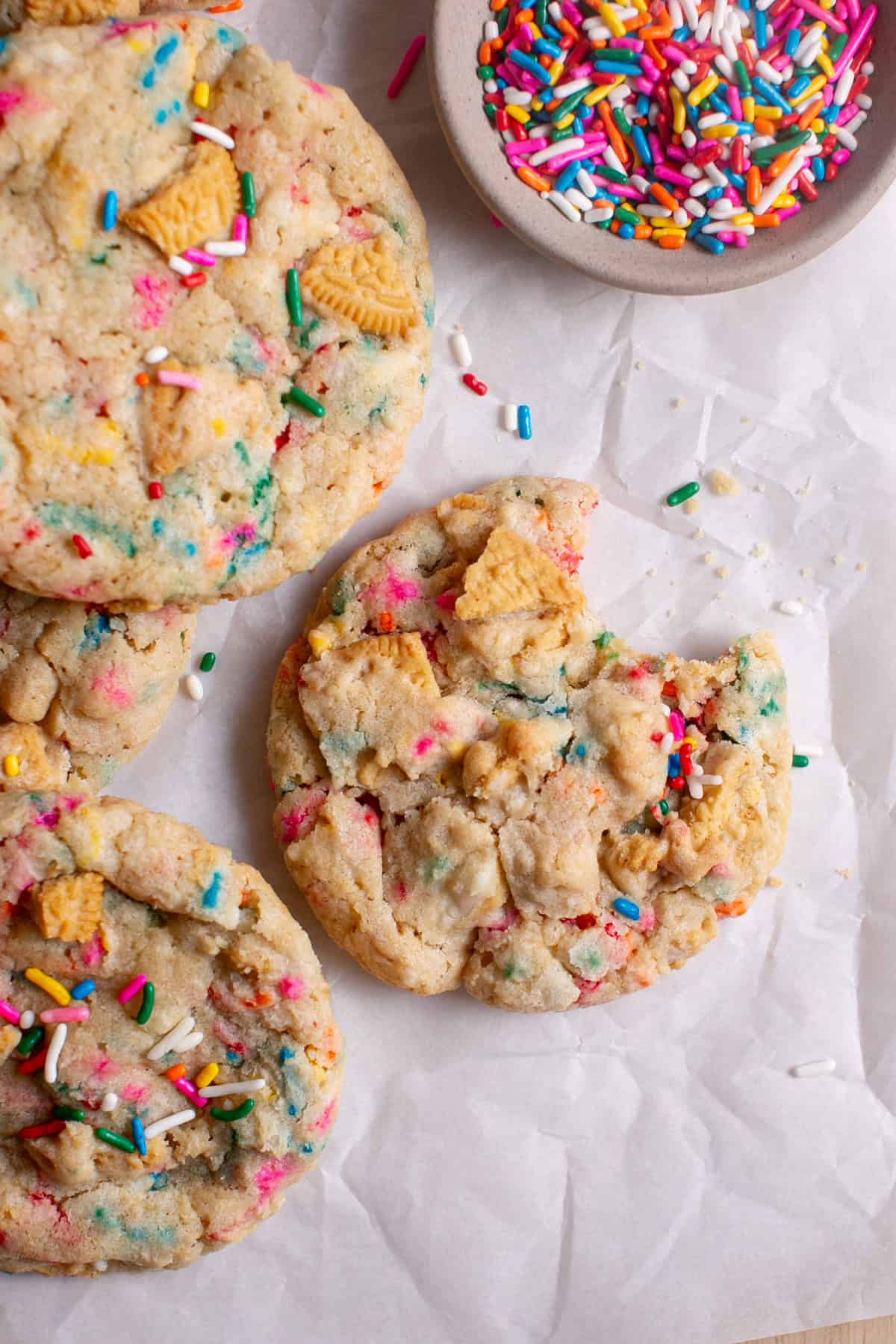 Golden Funfetti Cookies with a bite missing sitting by some crumbs.