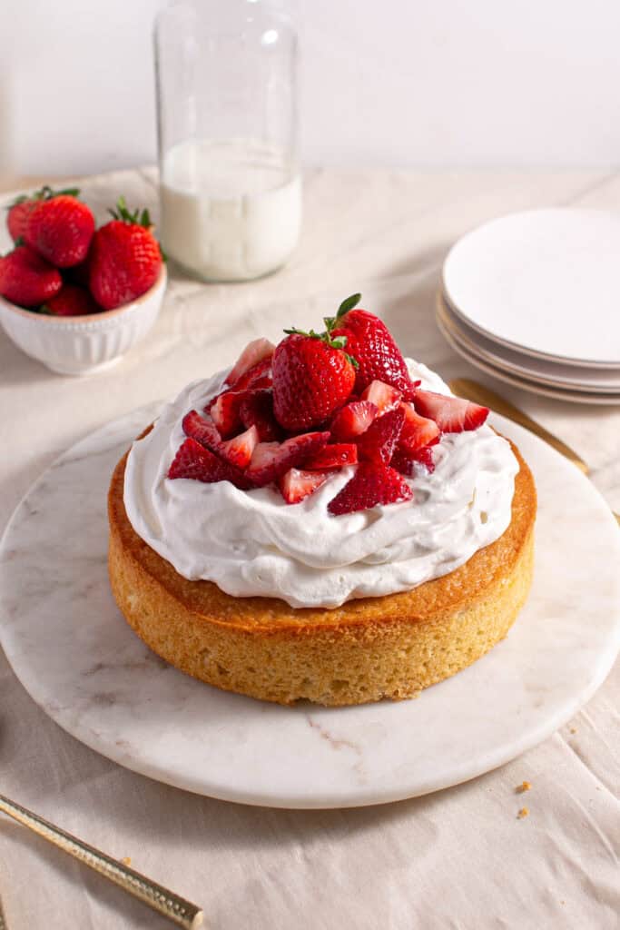 Small Batch Vanilla Cake sitting by a bowl of strawberries. 