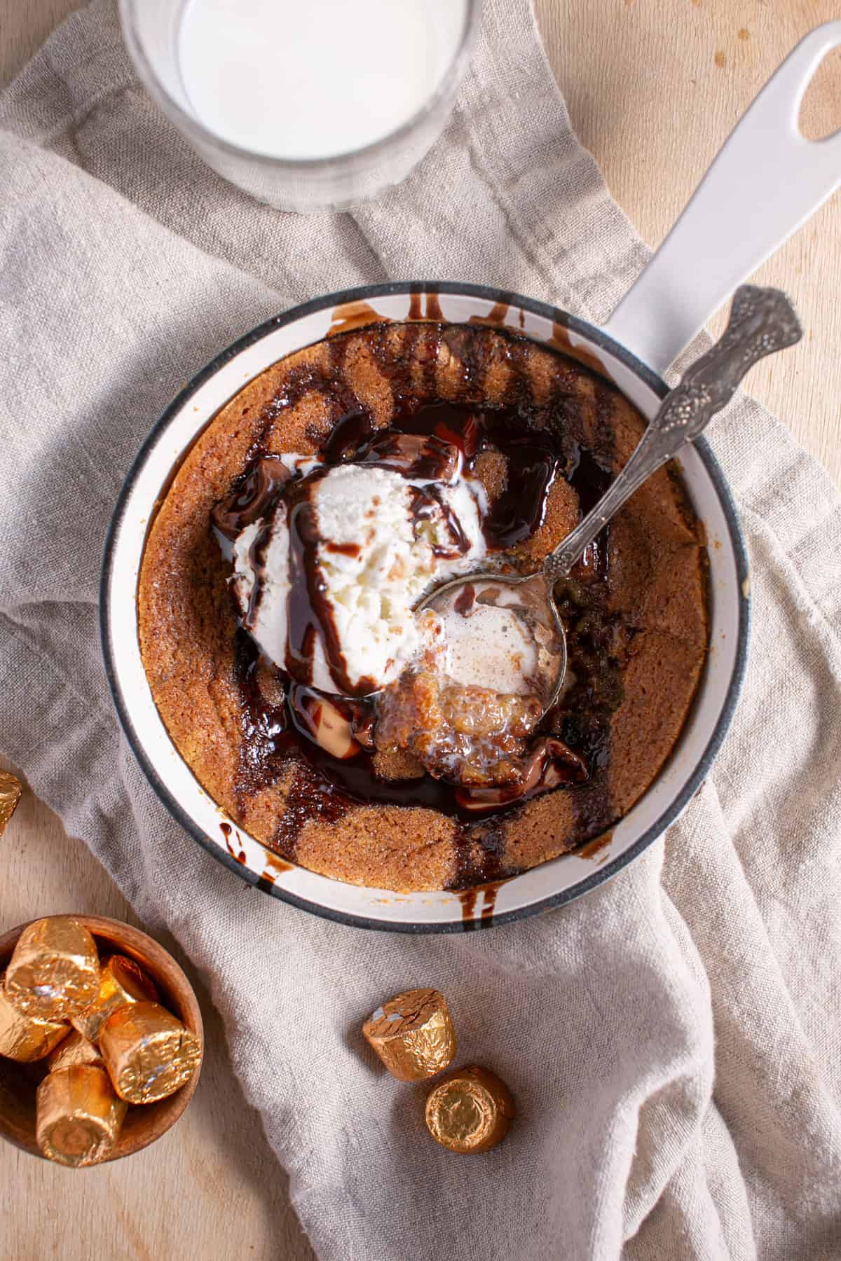 Skillet Chocolate Caramel Cookie sitting by a glass of milk.
