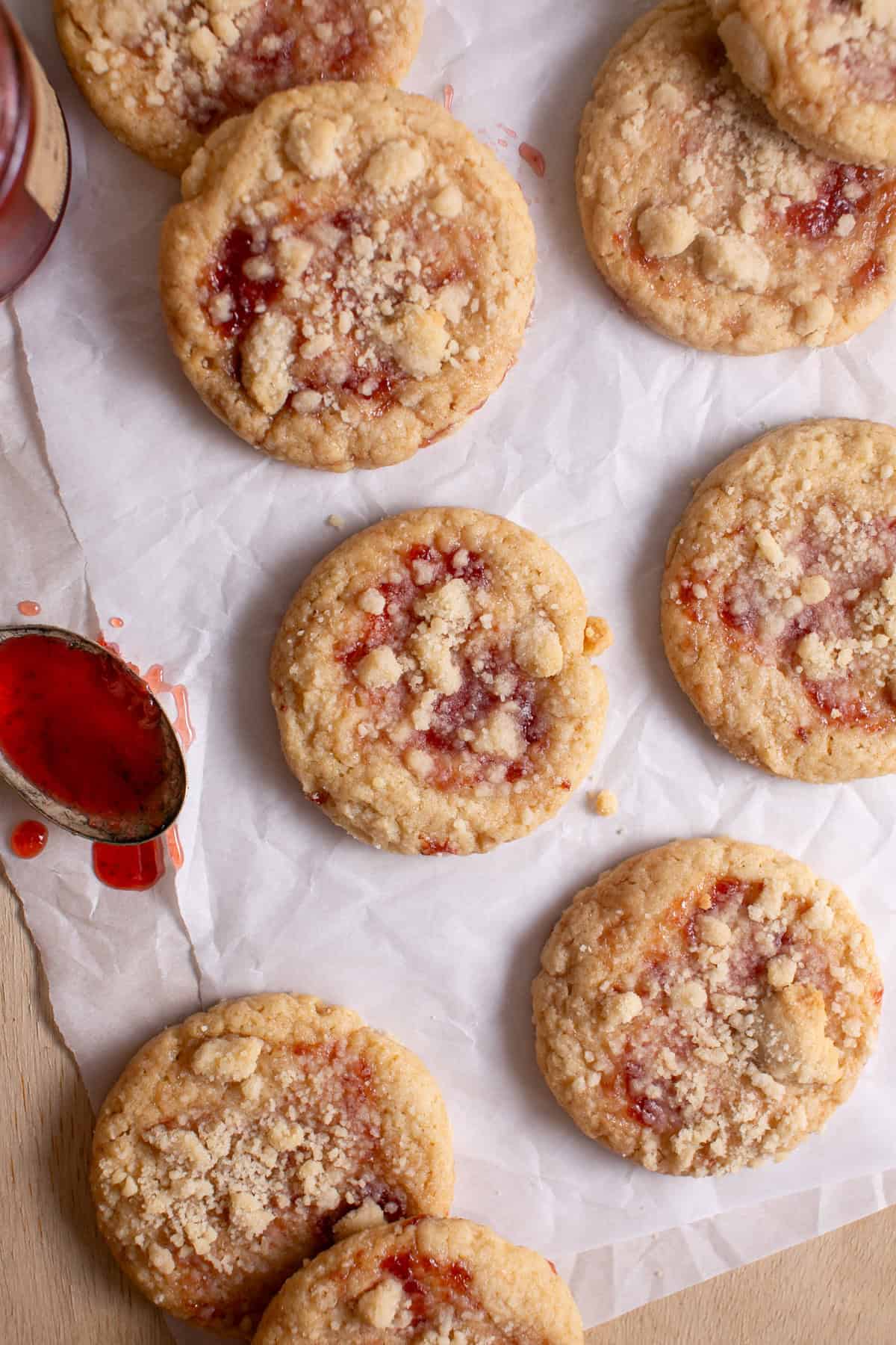 Strawberry Crumble Cookies on parchment paper with a spoon of jam.