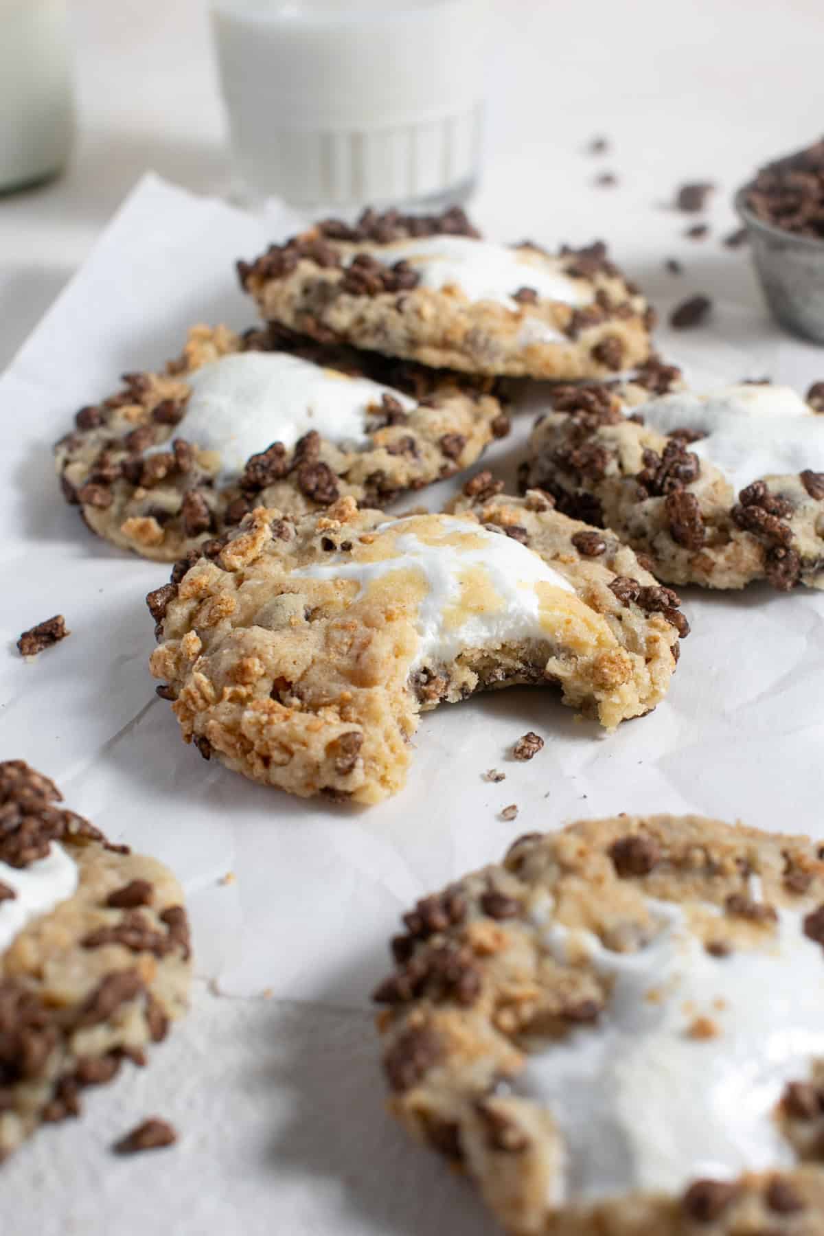 Chocolate Cereal S'mores Cookies sitting by a glass of milk.