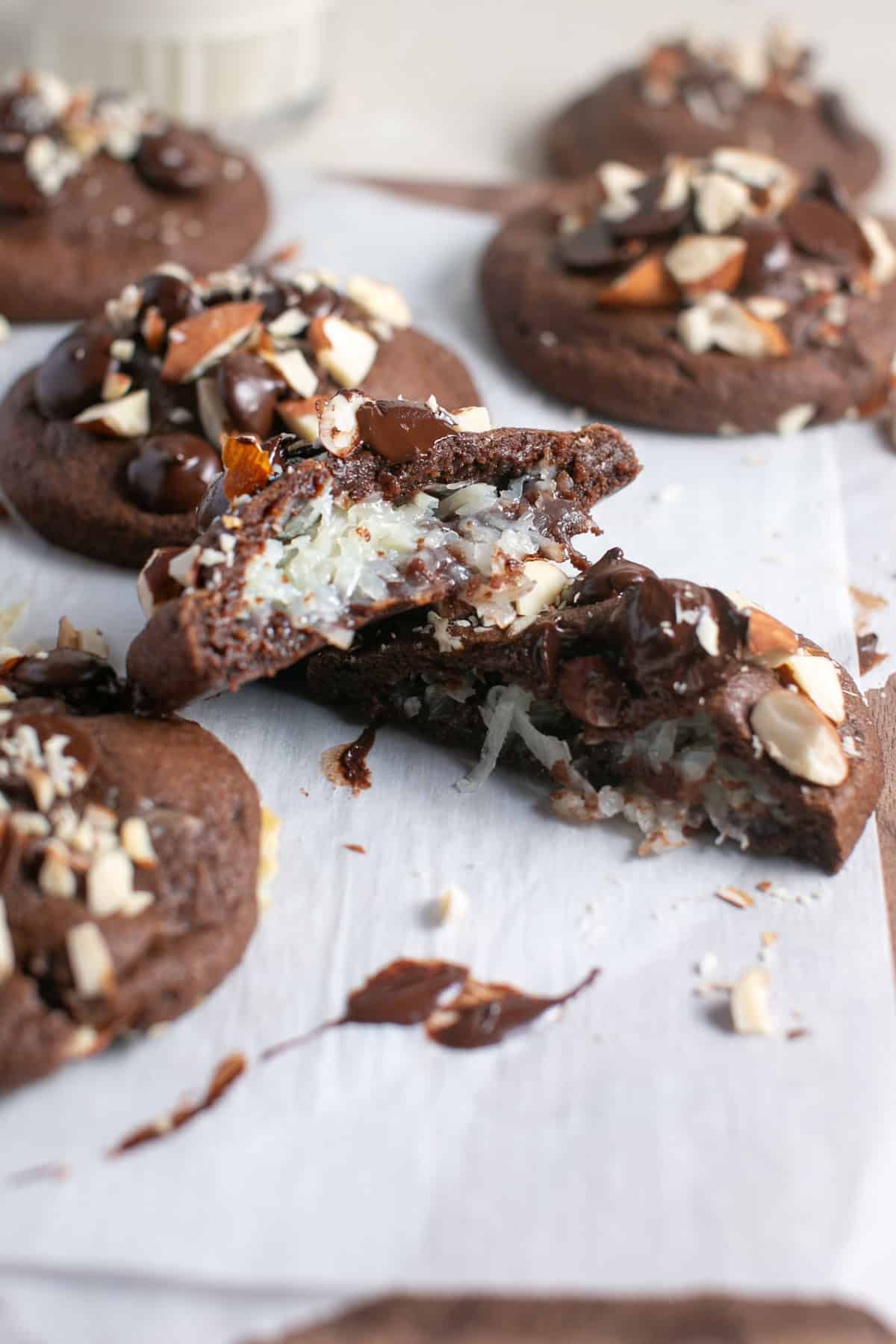 Almond joy cookies broken in half on parchment paper. 