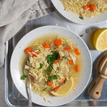 Chicken soup sitting by a juiced lemon.