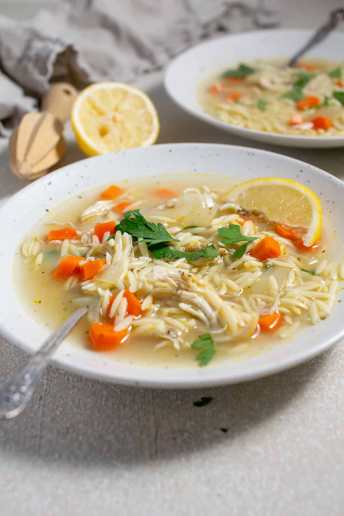 Lemon orzo soup with a slice of lemon.