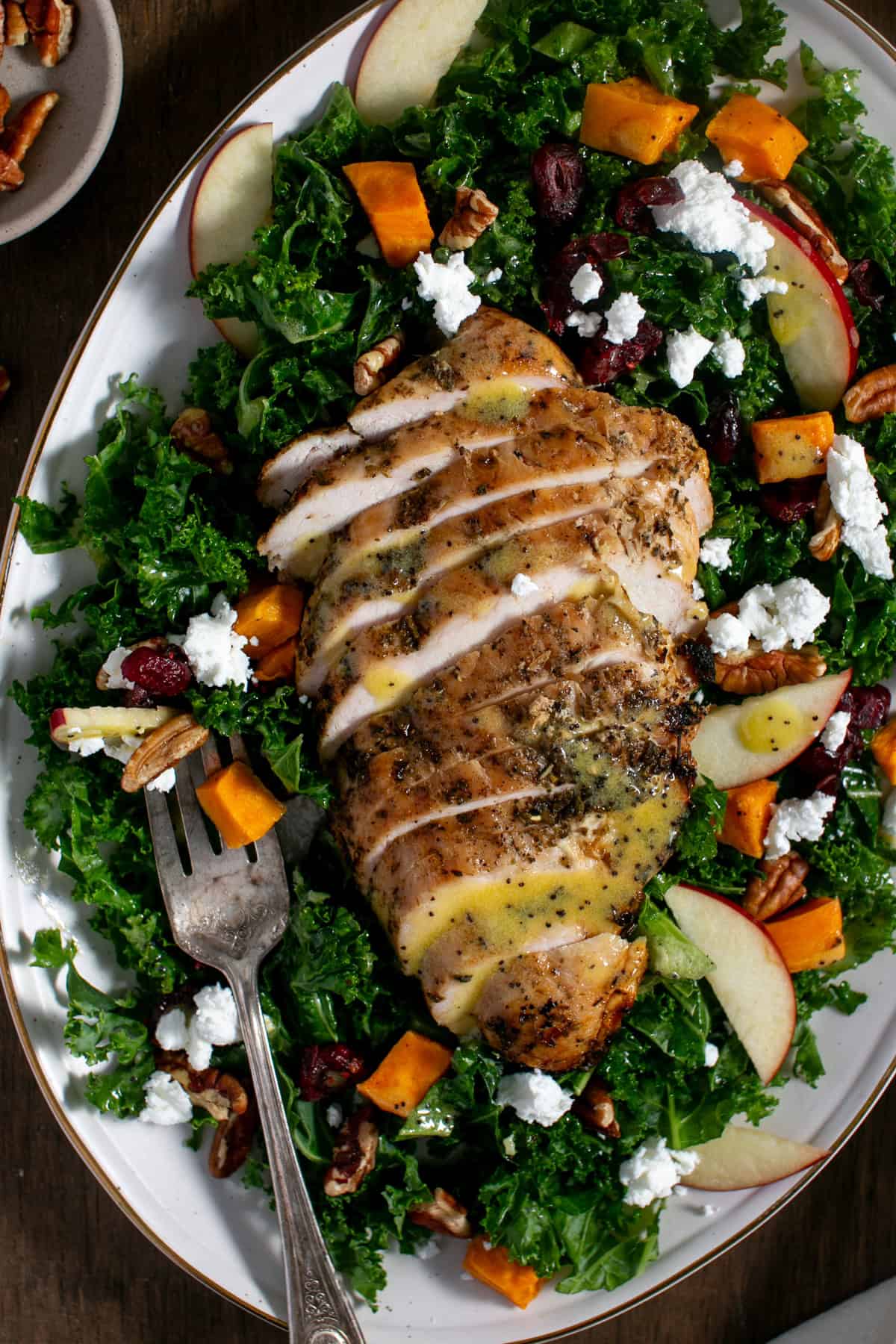 Sweet Potato Kale Salad with Honey Mustard Dressing sitting by a dish with pecans. 