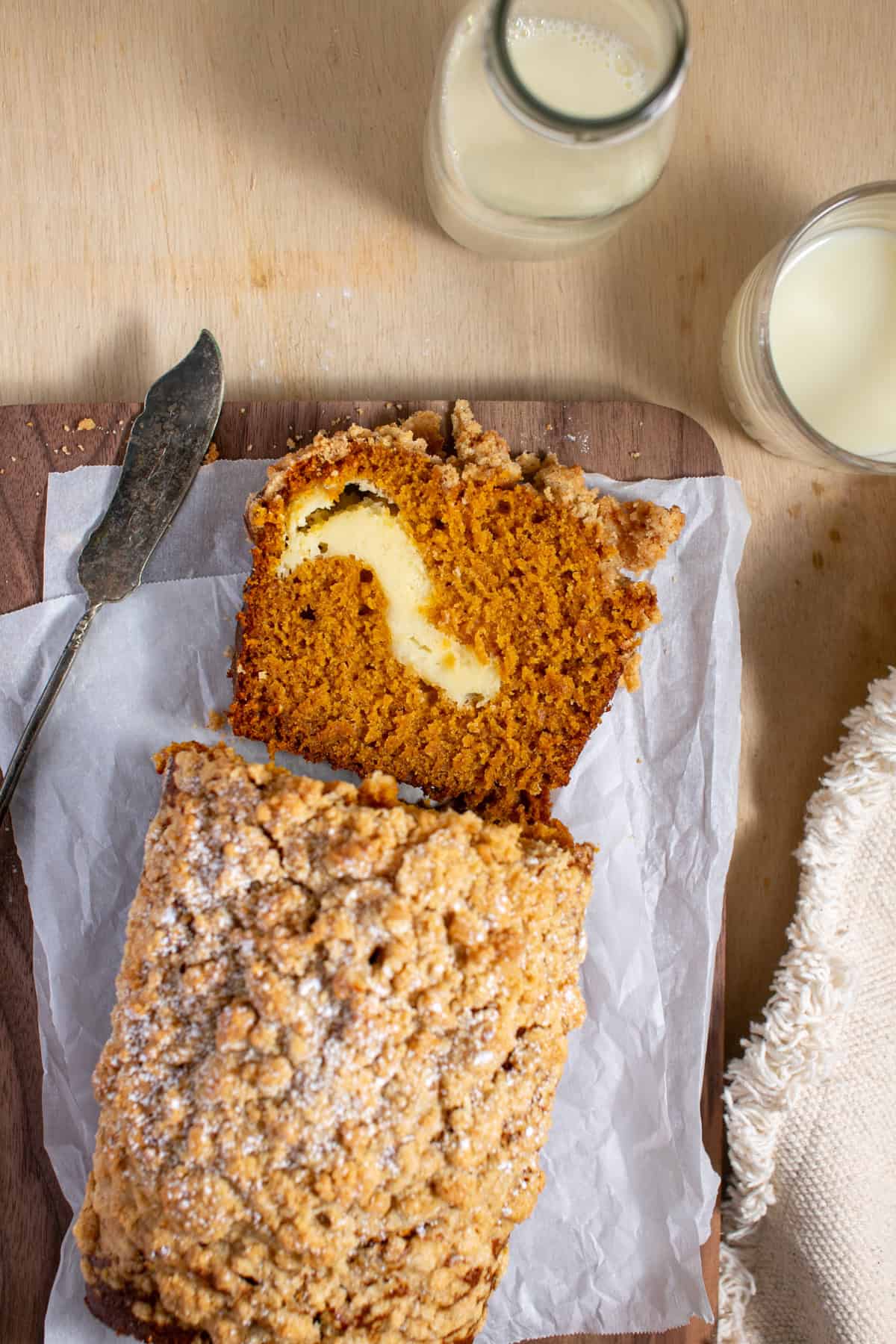 Cream Cheese Pumpkin Bread sliced on a cutting board sitting next to a butter knife.