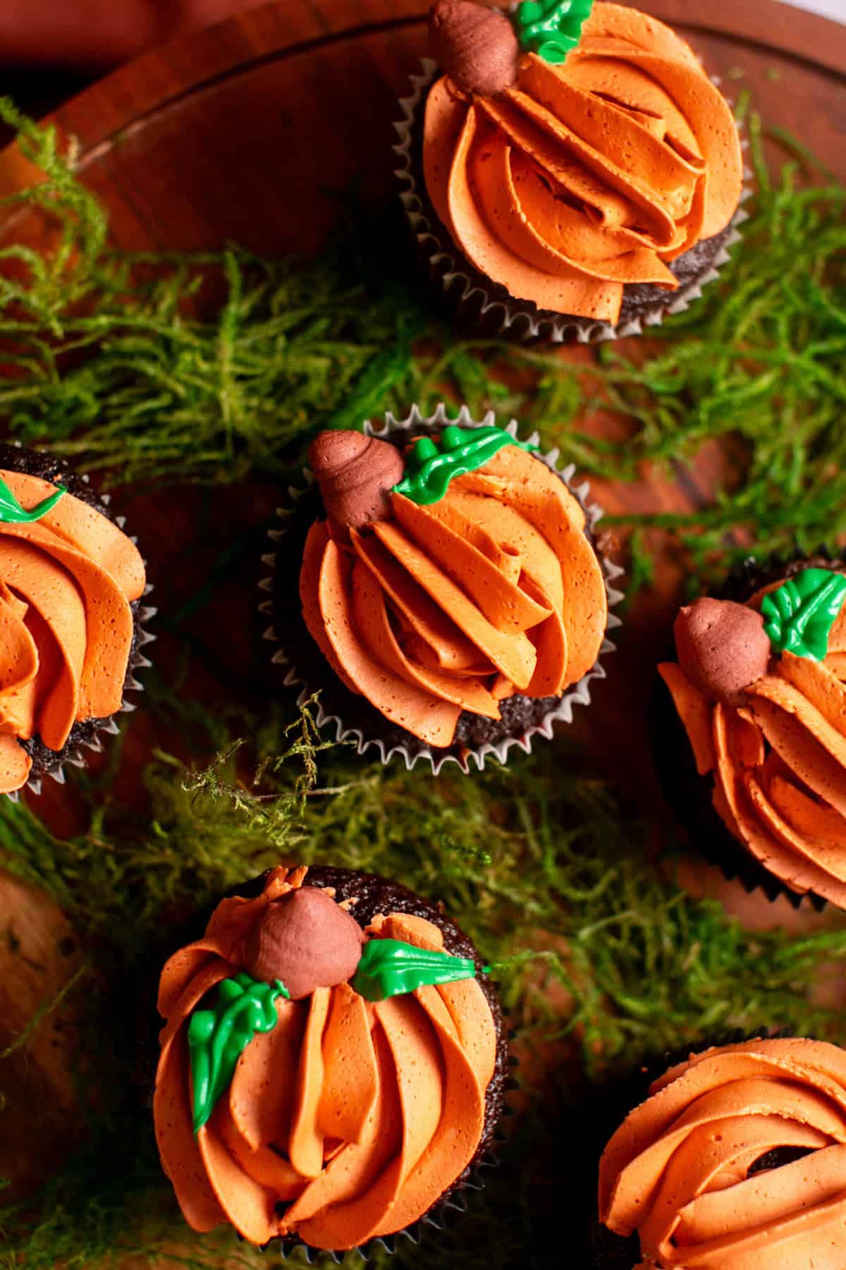 Halloween Pumpkin cupcakes sitting on a cake stand. 