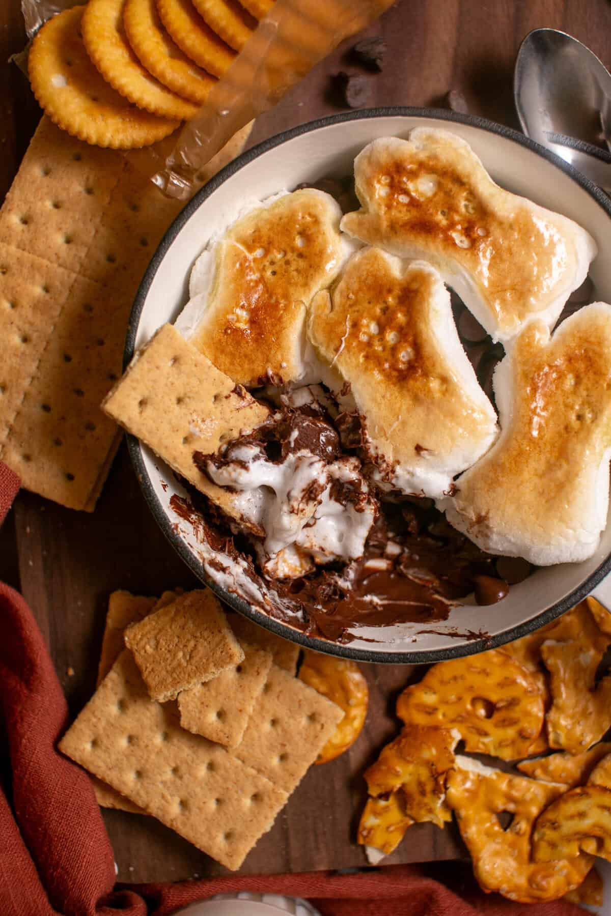 Halloween s'mores skillet with a graham cracker scooping out a marshmallow. 