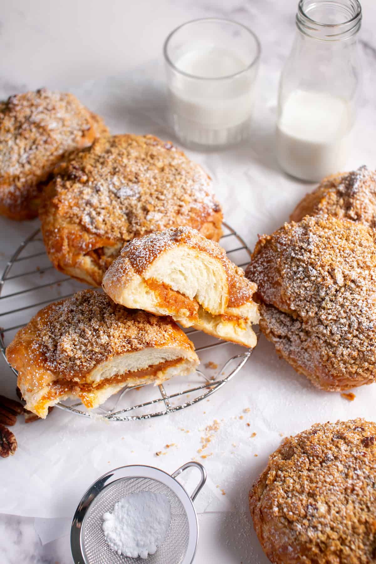 Pumpkin Pie Croissants on a cooling rack with a glass of milk.