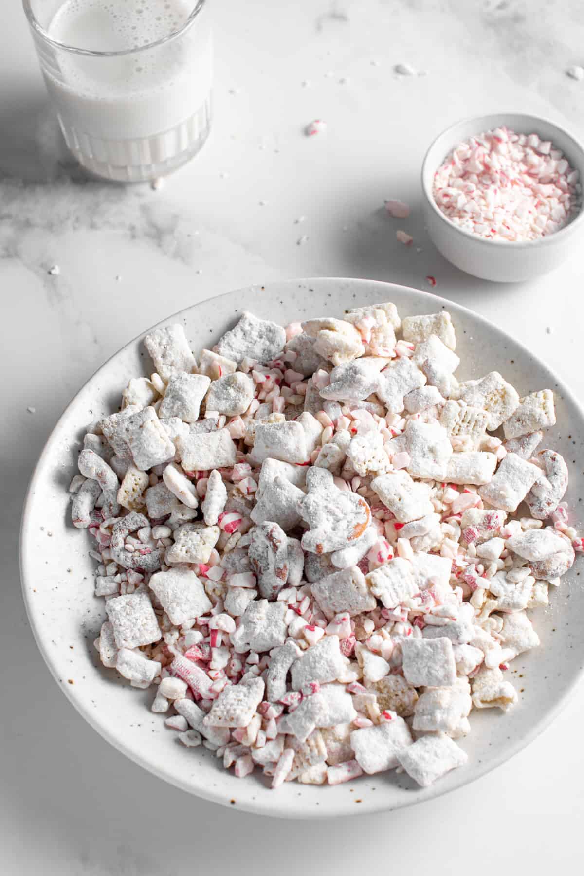 White Chocolate Peppermint Puppy Chow in a large bowl with peppermint pieces. 