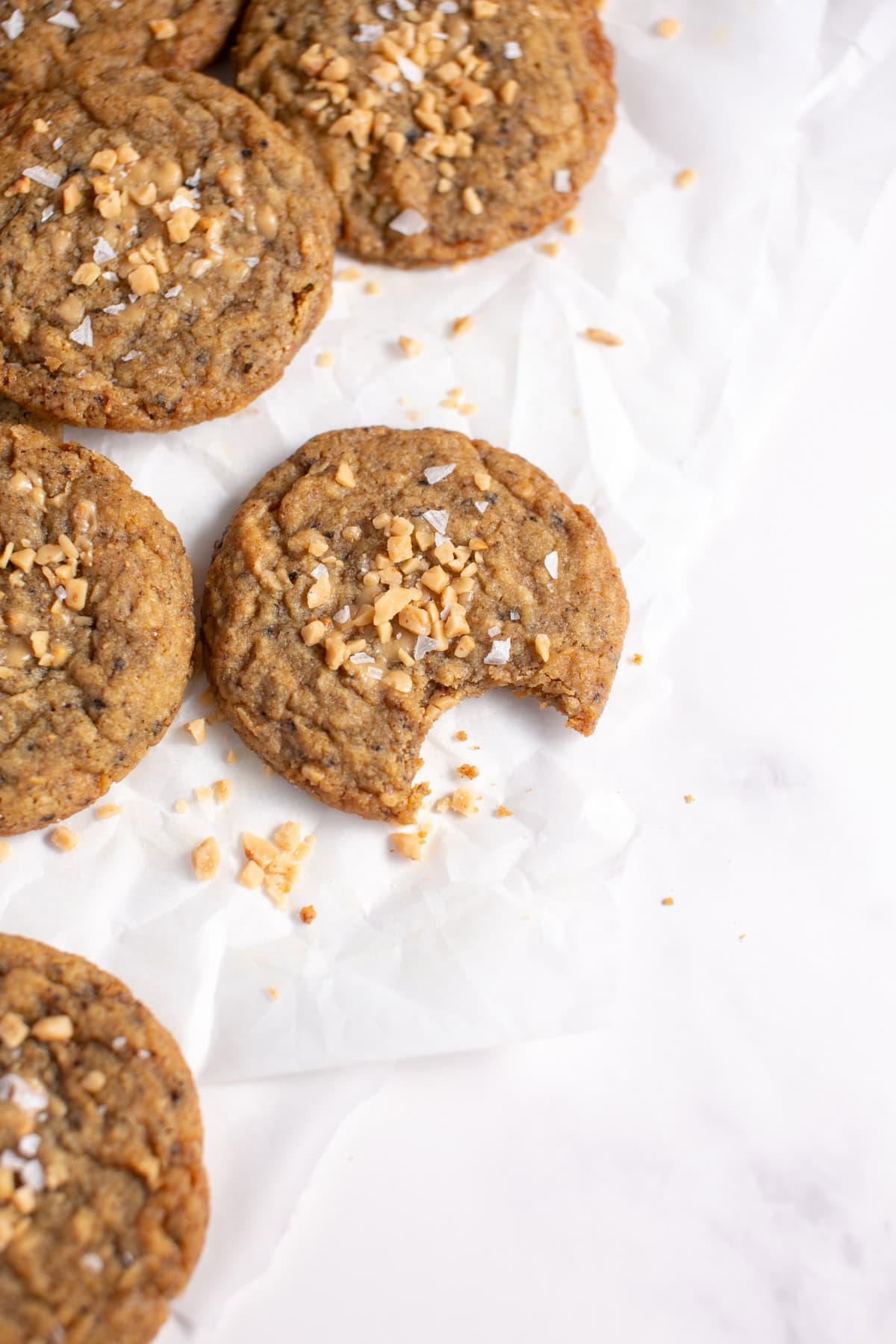 Toffee Coffee Browned Butter Cookie Recipe on parchment paper with a bite missing. 