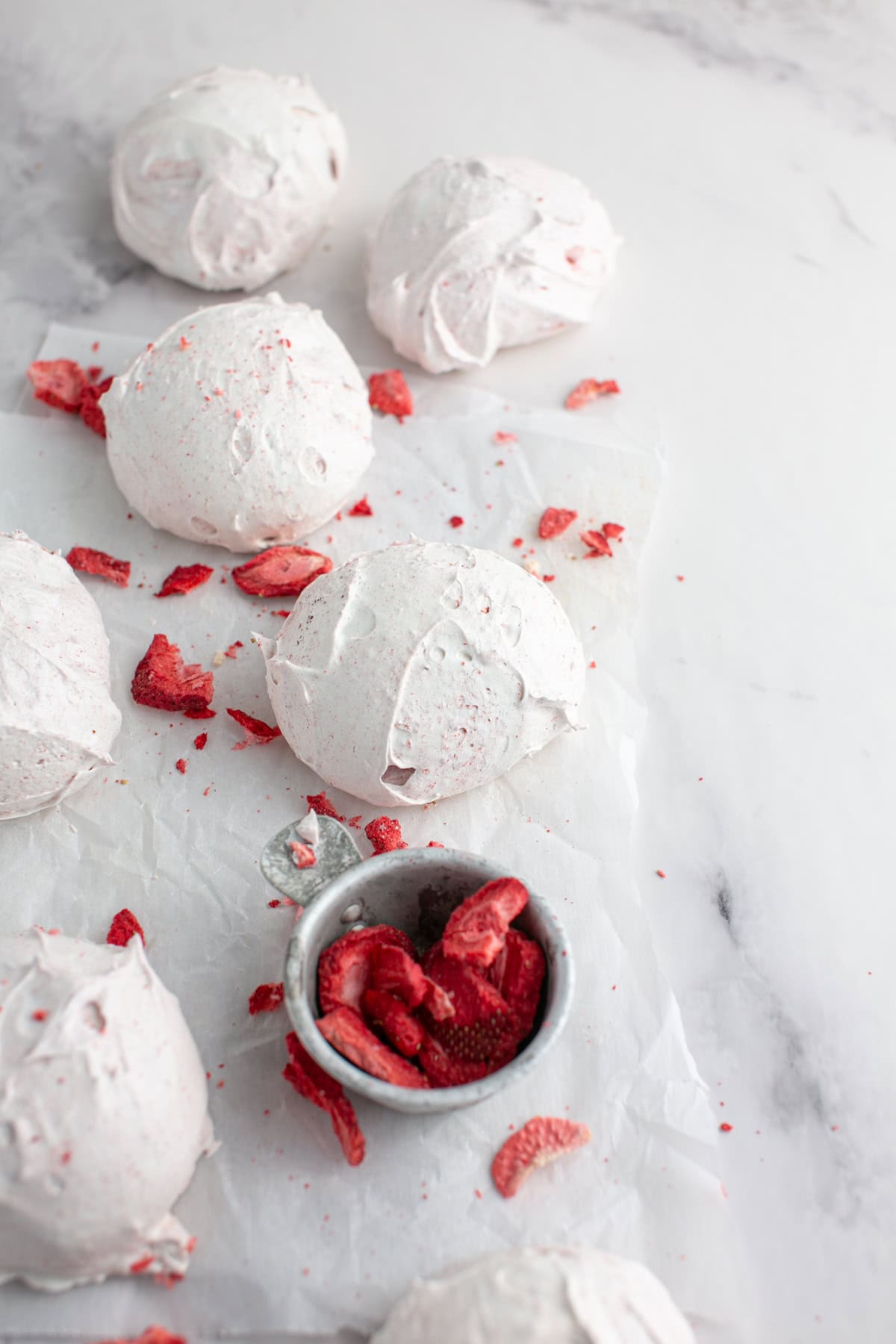 Strawberry Meringue Cloud Cookies by a bowl of strawberries.