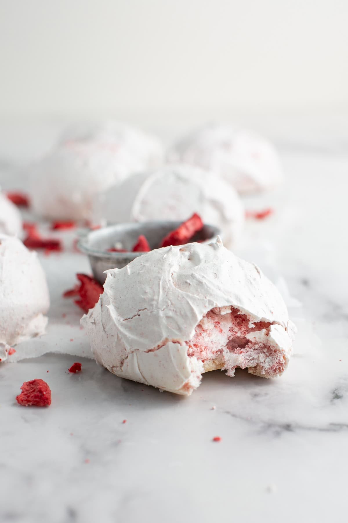 Strawberry Meringue Cloud Cookies with a bite missing by strawberries.