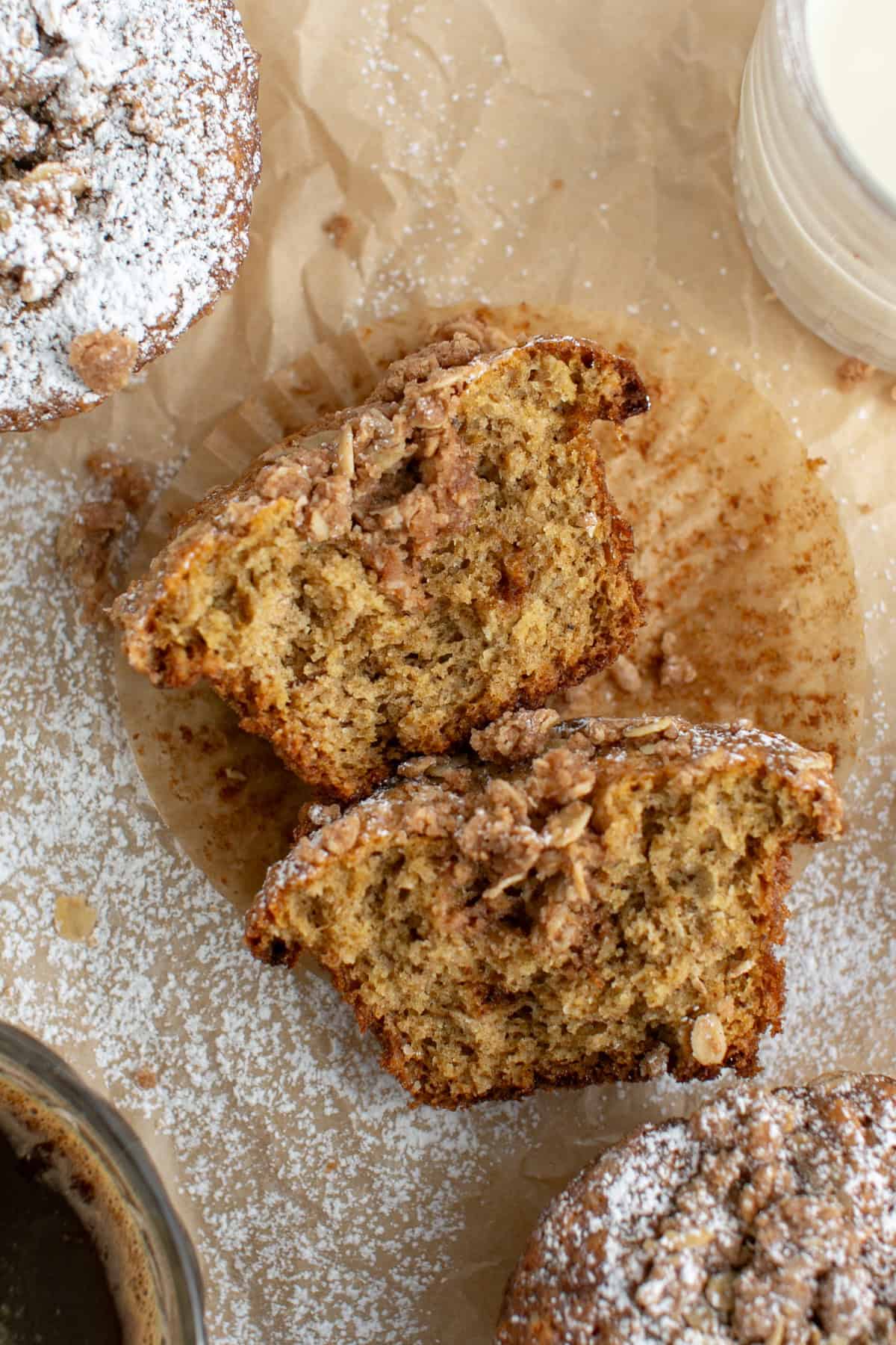 Chai Spiced Oat Crumble Muffins cut in half on parchment paper.